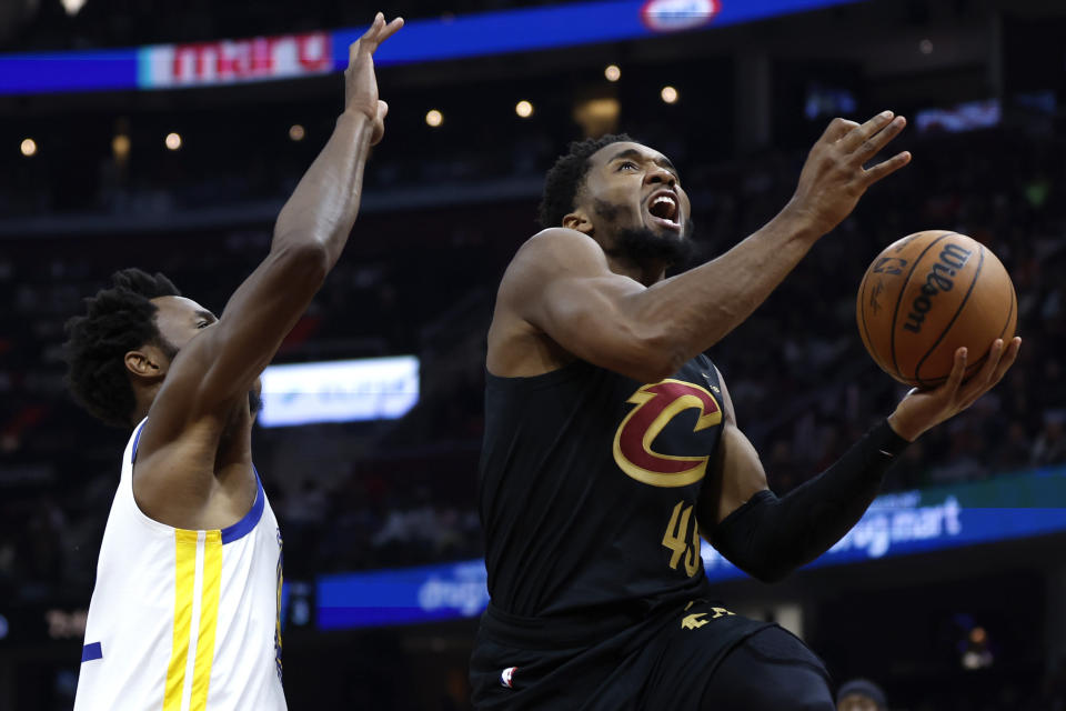 Cleveland Cavaliers guard Donovan Mitchell (45) shoots against Golden State Warriors forward Andrew Wiggins, left, during the first half of an NBA basketball game, Sunday, Nov. 5, 2023, in Cleveland. (AP Photo/Ron Schwane)