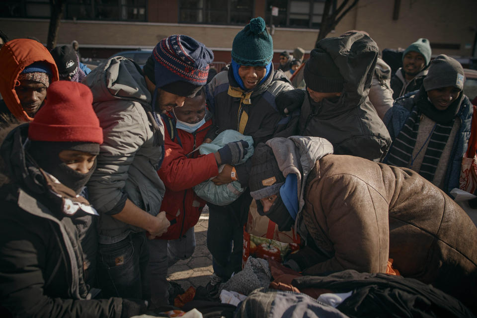 Migrants fight to get clothes as mutual aid groups distribute food and clothes under cold weather near the Migrant Assistance Center at St. Brigid Elementary School, on Saturday, Jan. 20, 2024, in New York. (AP Photo/Andres Kudacki)