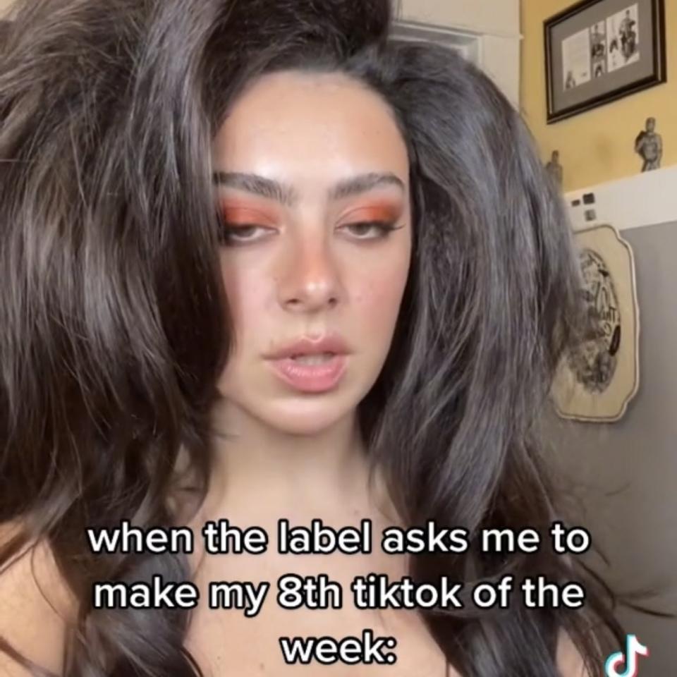 A screenshot of a depressed-looking Charli saying "When the label asks me to make my eighth TikTok of the week"
