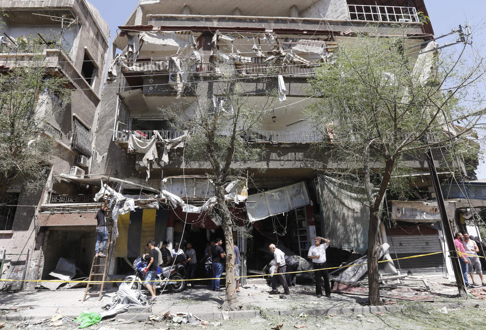 <p>TOPSHOT – Syrians inspect the damage at the site of a suicide bomb attack in the capital Damascus’ eastern Tahrir Square district, on July 2, 2017. (Louai Beshara/AFP/Getty Images) </p>