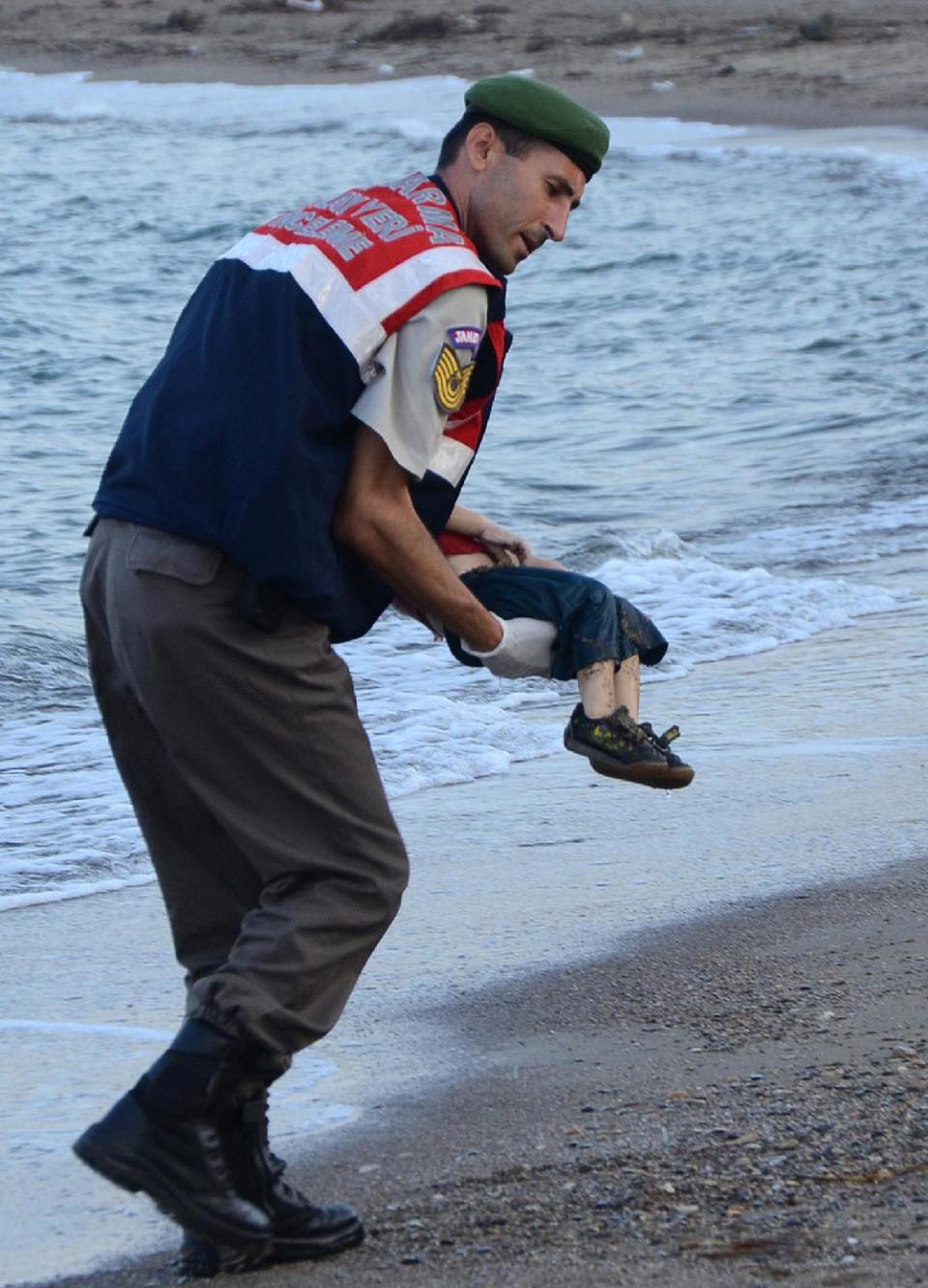 Un miembro de la policía turca recoge el cuerpo del niño sirio de 3 años ahogado, en una playa de Bodrum (Turquía) el 2 de septiembre de 2015 (Dogan News Agency/AFP | Str)