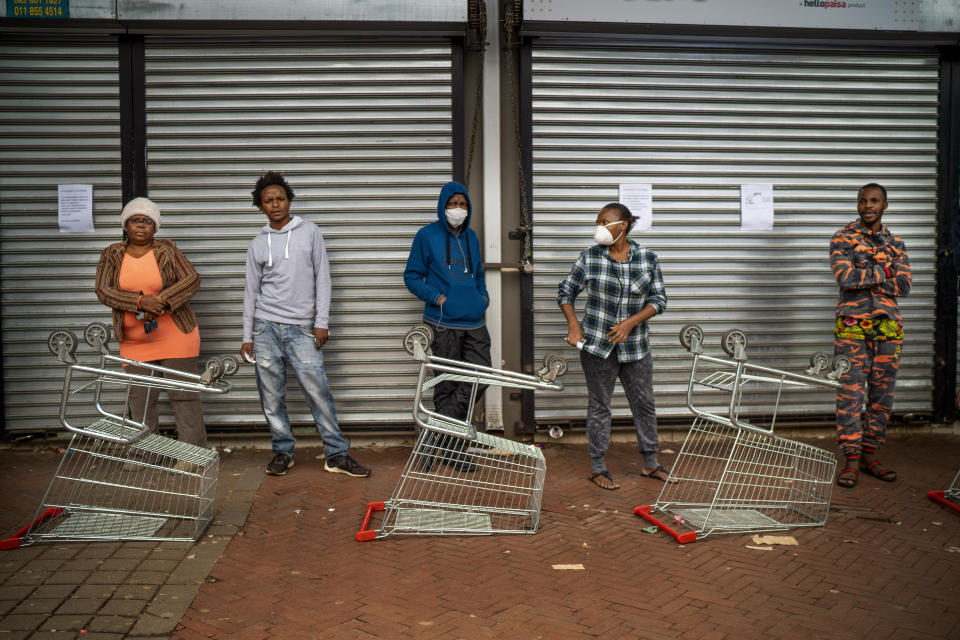 Residents of Yeoville neighborhood of Johannesburg, South Africa, wait in line to enter a grocery store Friday April 3, 2020. South Africa went into a nationwide lockdown for 21 days in an effort to control the spread of the coronavirus. The new coronavirus causes mild or moderate symptoms for most people, but for some, especially older adults and people with existing health problems, it can cause more severe illness or death.(AP Photo/Jerome Delay)