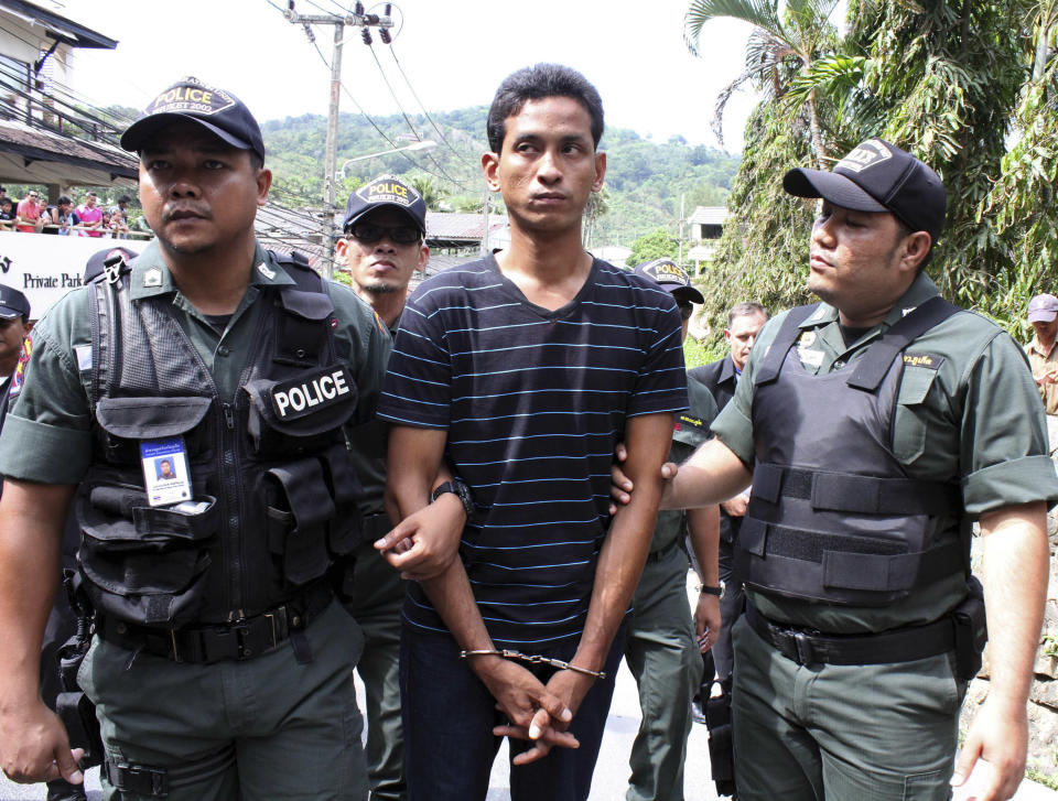 Surasak Suwannachote, 26, center, a Thai suspect of killing an Australian woman, is handcuffed and escorted for a police re-enactment in Phuket, southern Thailand Tuesday, June 26, 2012. Police arrested two Thai suspects in the slaying of an Australian woman who was stabbed to death when she resisted an attempt by two men on a motorcycle to snatch her bag on Thailand's resort island of Phuket. (AP Photo)