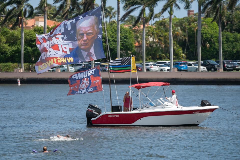 A pair of supporters of former President Donald Trump swim to a boat decorated with Trump flags anchored in the Lake Worth Lagoon near Mar-A-Lago, Trump's residence, on Saturday, April 1, 2023, in Palm Beach, FL.