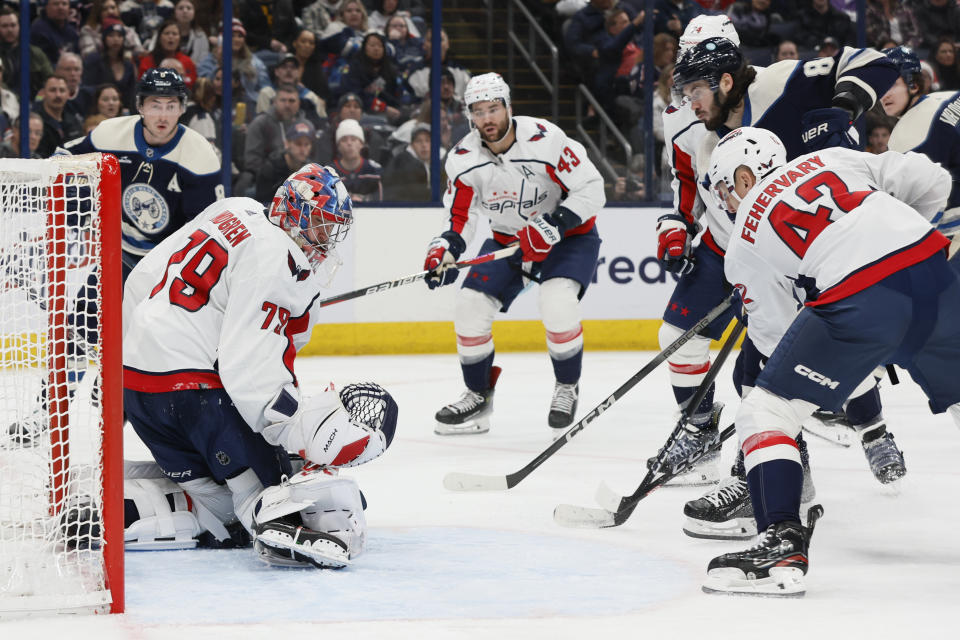 Washington Capitals' Charlie Lindgren, left, makes a save as Martin Fehervary, right, front, and Columbus Blue Jackets' Kirill Marchenko look for the rebound during the second period of an NHL hockey game Thursday, Dec. 21, 2023, in Columbus, Ohio. (AP Photo/Jay LaPrete)