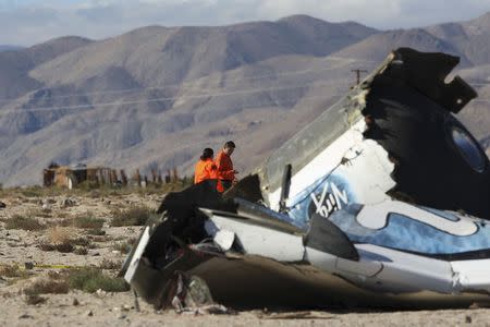 Sheriffs' deputies look at wreckage from the crash of Virgin Galactic's SpaceShipTwo near a broken down house near Cantil, California November 2, 2014. REUTERS/David McNew