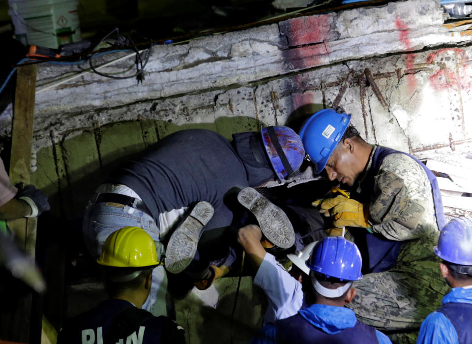 <p>Members of a rescue team hold a fellow rescuer from the Topos volunteer search and rescue group by his feet during the search for students at the Enrique Rebsamen school after an earthquake in Mexico City, Mexico, Sept. 21, 2017. (Photo: Daniel Becerril/Reuters) </p>