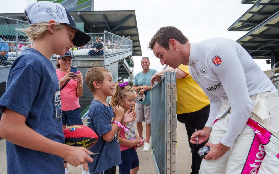 Andretti Autosport driver Kyle Kirkwood (27) sits autographs Friday, Aug. 11, 2023, for young fans after qualifying in preparation for the Gallagher Grand Prix on Saturday at Indianapolis Motor Speedway.