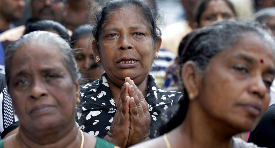 Sri Lankan Catholics pray on a road during a brief holly Mass held outside the exploded St. Anthony's Church. Source AP.