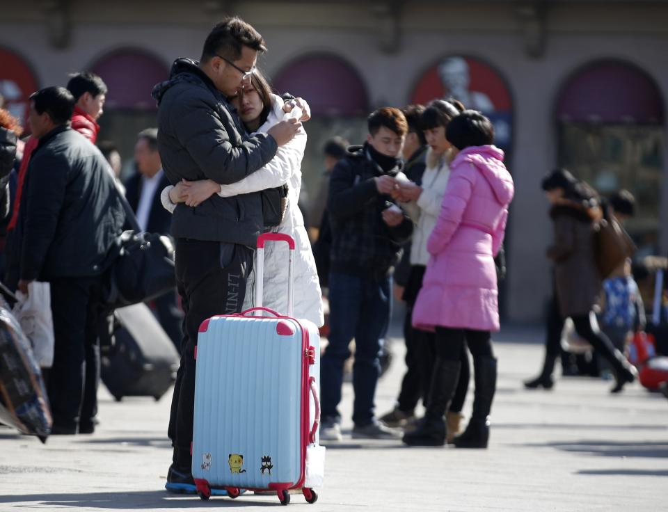 A couple hugs each other as they prepare to go to their hometowns at a railway station in Beijing