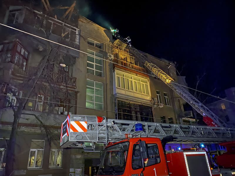 Ukrainian firefighters work at a site of an apartment building severely damaged by a Russian missile in Kharkiv