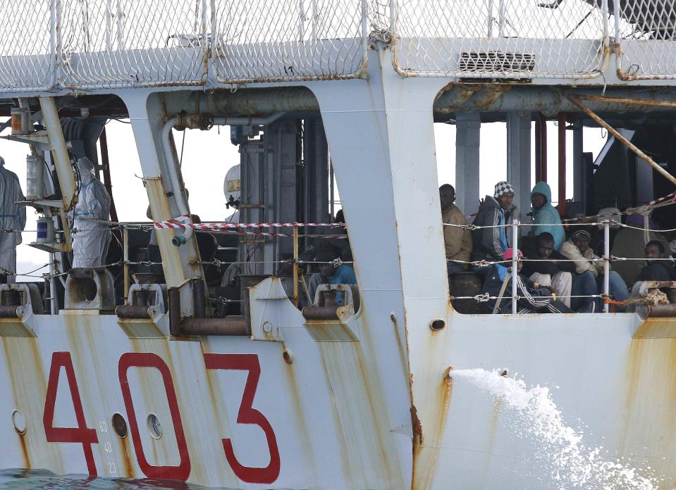 Migrants sit on the Italian Navy patrol ship Spica, as they arrive at the Sicilian harbour of Pozzallo