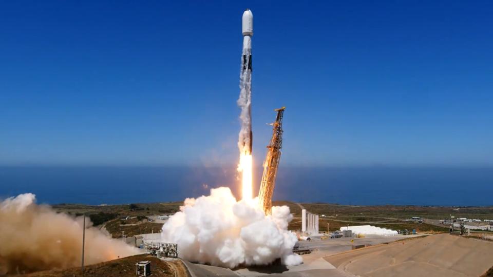  A rocket lifting off in front of a blue sky. 