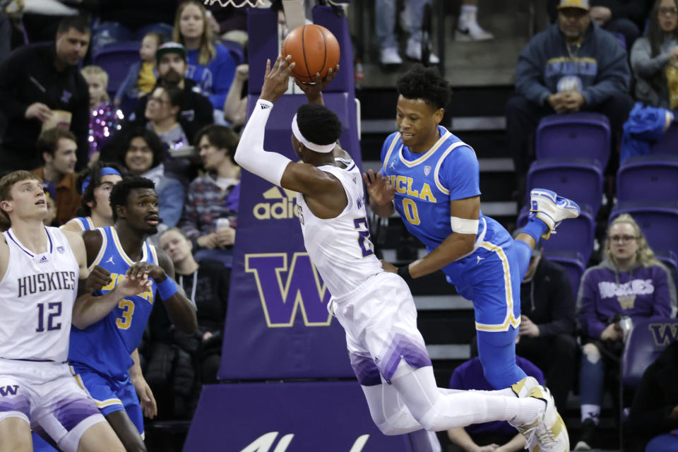 Washington guard Noah Williams draws a foul from UCLA guard Jaylen Clark during the first half of an NCAA collage basketball game, Sunday, Jan. 1, 2023, in Seattle. (AP Photo/John Froschauer)