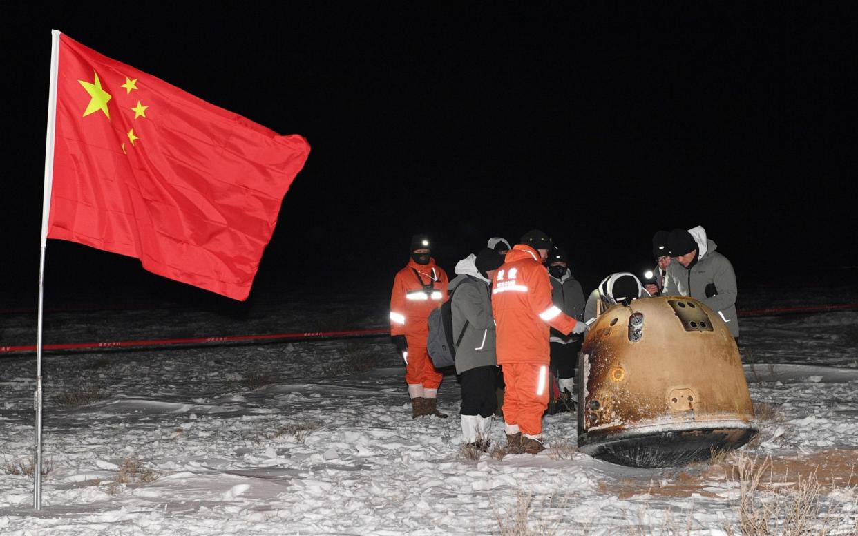 Researchers work around Chang'e-5 lunar return capsule carrying moon samples next to a Chinese national flag, after it landed in northern China's Inner Mongolia Autonomous Region - Reuters