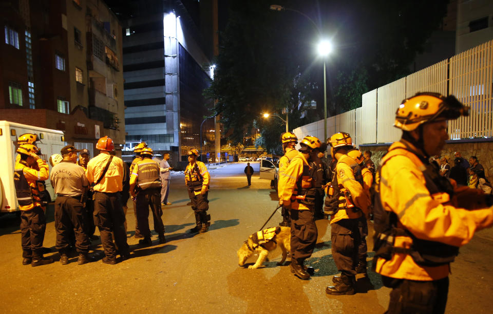 Civil Protection workers patrol near the "Tower of David" skyscraper, which suffered an inclination after a powerful earthquake shook eastern Venezuela, causing buildings to be evacuated in the capital of Caracas, Venezuela, Tuesday, Aug. 21, 2018. The quake was felt as far away as Colombia's capital and in the Venezuelan capital office workers evacuated buildings and people fled homes. (AP Photo/Ariana Cubillos)