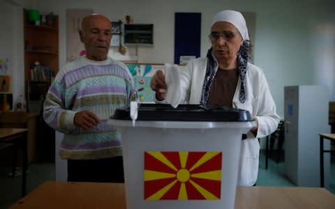 An ethnic Albanian woman casts her ballot at a polling station in Skopje, Macedonia - Credit: Thanassis Stavrakis/AP