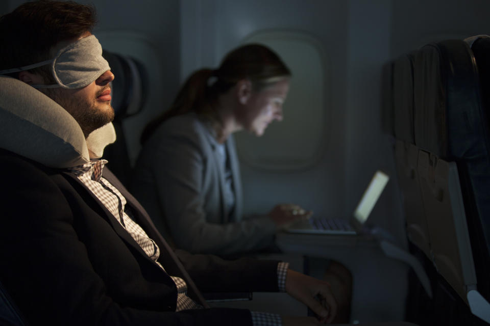 Man asleep on plane with eye mask and neck pillow