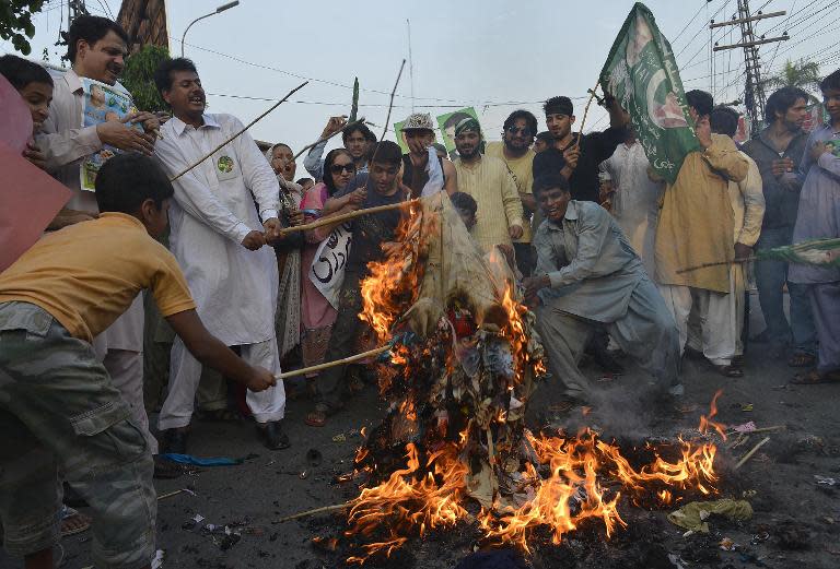 Pakistani supporters of ruling party Pakistan Muslim League-Nawaz (PML-N) torch effiges of cleric Tahir-ul-Qadri and opposition leader Imran Khan during a protest in Lahore on August 11, 2014