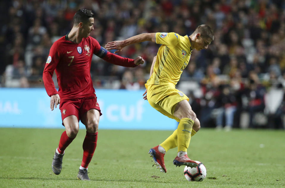 Portugal's Cristiano Ronaldo, left, challenges for the ball with Ukraine's Vitaliy Mykolenko during the Euro 2020 group B qualifying soccer match between Portugal and Ukraine at the Luz stadium in Lisbon, Friday, March 22, 2019. (AP Photo/Armando Franca)