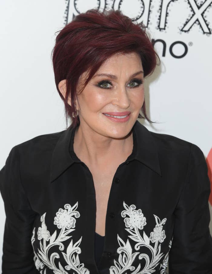 Woman with short hair wearing a black shirt with white embroidery at an event