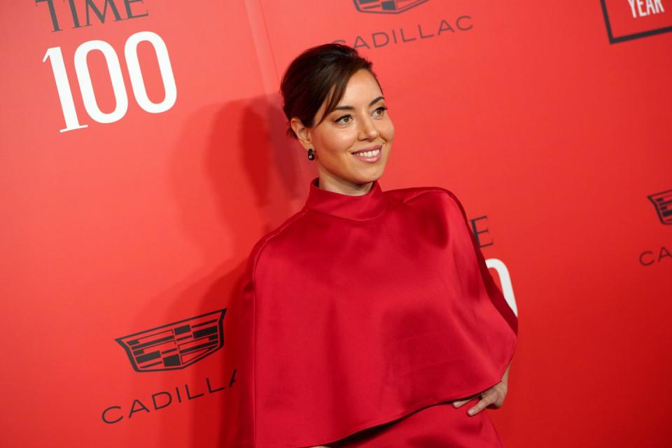 aubrey plaza wearing a red dress at a gala event and posing for a photo