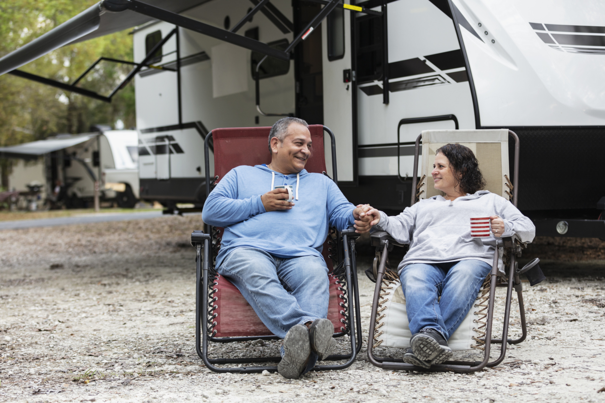 Couple Sitting in Chairs by Camper in Front of RV at a Campsite