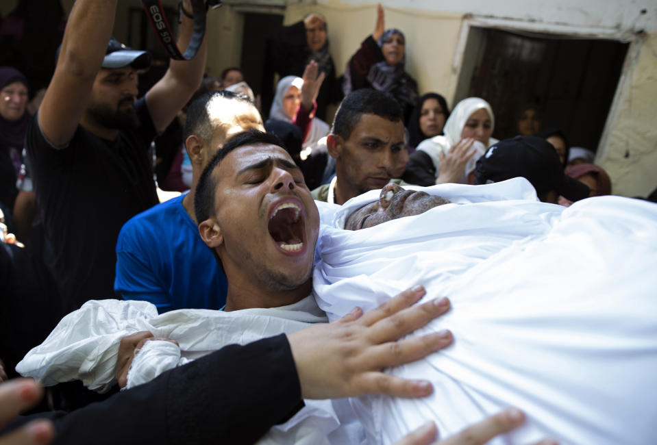 Mourners chant angry slogans as they carry the body of Palestinian Hamas police officer, Wael Khalifa, 45, in the family home, during his funeral in the Buriej refugee camp, central Gaza Strip, Wednesday, Aug. 28, 2019. Khalifa and two other Hamas police officers were killed in explosions that ripped through police checkpoints in Gaza City overnight, Hamas' interior ministry said. (AP Photo/Khalil Hamra)