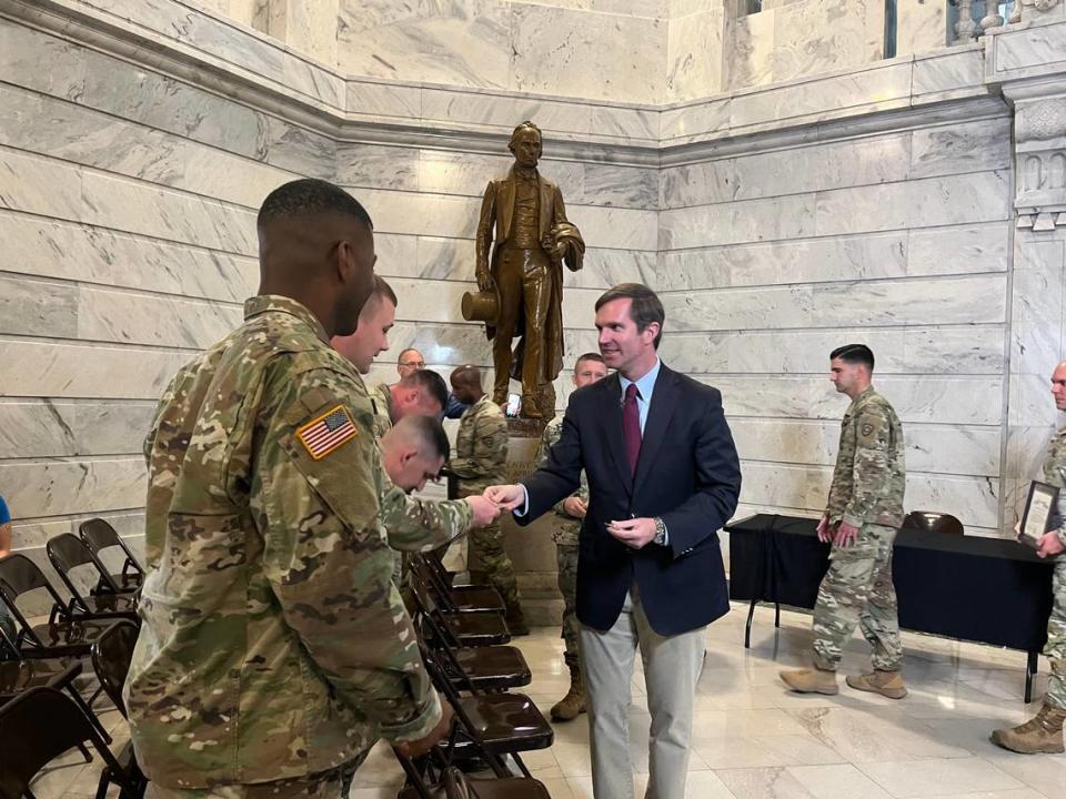 Beshear hands out Team Kentucky branded coins to National Guard members at an event honoring those deployed to the U.S.-Mexico border. Austin Horn