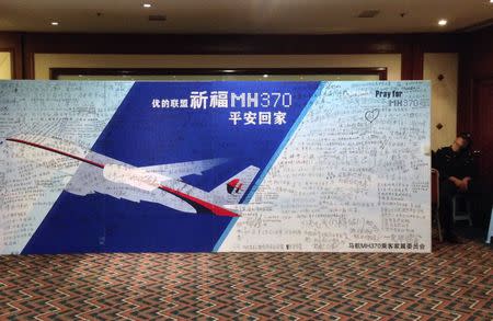 A policeman takes a nap beside a board written with messages for passengers onboard the missing Malaysia Airlines Flight MH370 during a closed meeting held between Malaysian representatives and Chinese relatives of passengers on Flight MH370 at Lido Hotel in Beijing May 2, 2014. REUTERS/Jason Lee