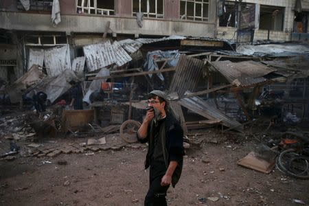 A man covers his nose as he walks along a damaged site hit by missiles fired by Syrian government forces on a busy marketplace in the Douma neighborhood of Damascus, Syria October 30, 2015. REUTERS/Bassam Khabieh