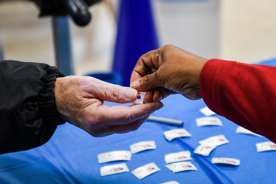 Voting Judge Gloria Wise hands out "I voted" stickers at the Allen community hall on Tuesday, Nov 6, 2018.