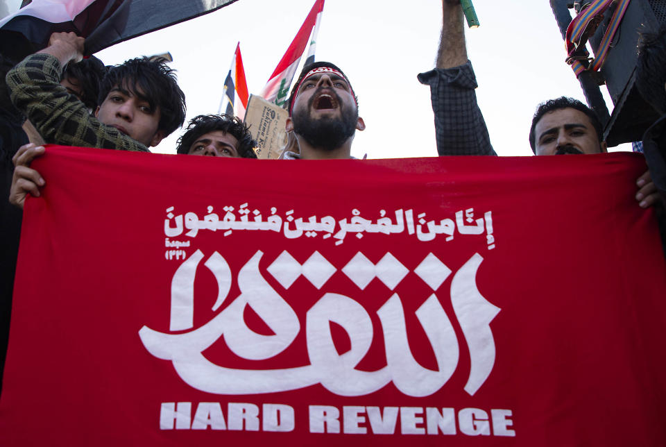 A man holds a slogans in Arabic calling for revenge as the body of Abu Mahdi al-Muhandis, the slain chief of Hashed al-Shaabi, an Iraqi paramilitary force with close ties to Iran, arrives in the southern city of Basra after it came from Iran on January 7, 2019 ahead on his burial. - Muhandis, killed early on January 3 in a US strike on Baghdad, was seen as Tehran's man in Iraq and a sworn enemy of the United States. The US strike on Baghdad's international airport early Friday also killed his personal friend Qasem Soleimani, a top commander in Iran's Revolutionary Guard Corps. (Photo by Hussein FALEH / AFP) (Photo by HUSSEIN FALEH/AFP via Getty Images)