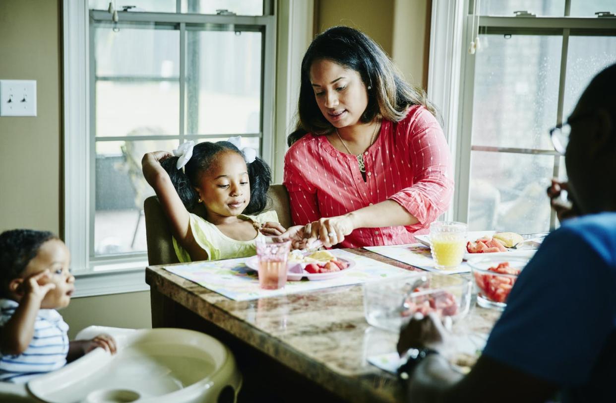 <span class="caption">Moms and dads have better physical and mental health when they dine with their children – despite all the work of a family meal.</span> <span class="attribution"><a class="link " href="https://www.gettyimages.com/detail/photo/mother-cutting-daughters-food-at-breakfast-royalty-free-image/659856885" rel="nofollow noopener" target="_blank" data-ylk="slk:Thomas Barwick/DigitalVision via Getty Images;elm:context_link;itc:0;sec:content-canvas">Thomas Barwick/DigitalVision via Getty Images</a></span>