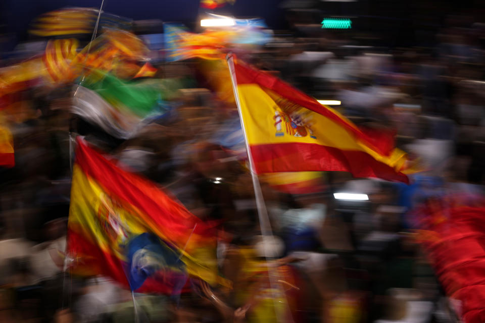 Simpatizantes del Partido Popular ondean banderas de España mientras esperan la comparecencia de su candidato a la presidencia, Alberto Núñez Feijóo, en el exterior de la sede de la formación conservadora durante la noche electoral, el 23 de julio de 2023, en Madrid. (AP Foto/Manu Fernández)