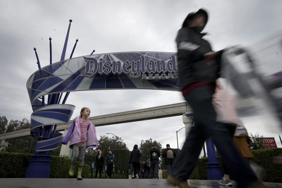 Visitors to Disneyland make their way in and out of the parks Thursday, March 12, 2020, in Anaheim, Calif. Walt Disney Co. is shutting both its Disneyland and California Adventure amusements parks in Anaheim on Saturday, for the rest of the month. (AP Photo/Chris Carlson)