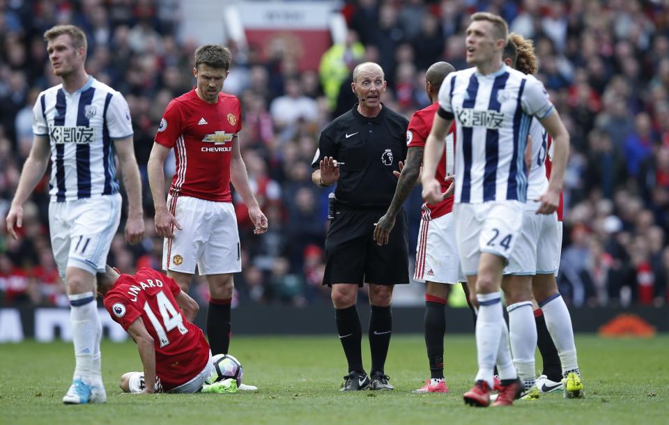 <p>Referee Mike Dean speaks to Manchester United’s Ashley Young as Jesse Lingard is down </p>