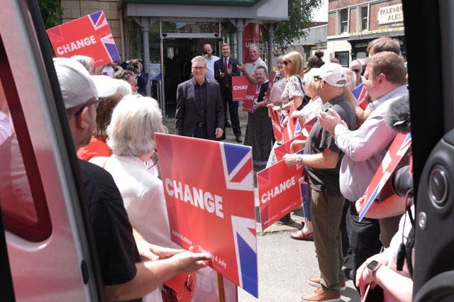 Sir Keir Starmer with a group of people holding red placards reading ChangeGeneral Election campaign 2024