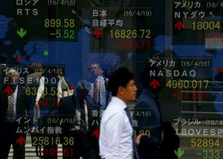 A man walks past a display of the Nikkei average and other market indices outside a brokerage in Tokyo, Japan April 19, 2016. REUTERS/Thomas Peter