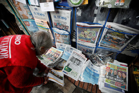 A woman sells newspapers that show candidates Gustavo Petro and Ivan Duque go to the second round of presidential election, in Bogota, Colombia May 28, 2018. REUTERS/Jaime Saldarriaga