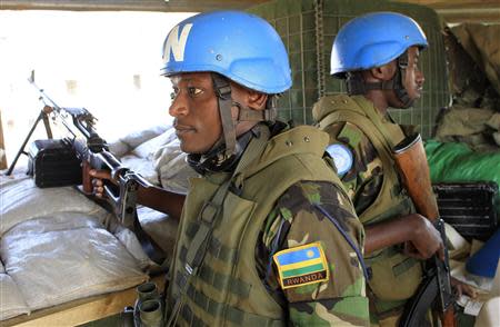 Soldiers from Rwanda serving under United Nations Mission in South Sudan (UNAMISS) hold their weapons as they keep watch from an observatory point at Tomping camp, where some 15,000 displaced people who fled their homes are sheltered by the United Nations, near Juba January 7, 2014. REUTERS/James Akena