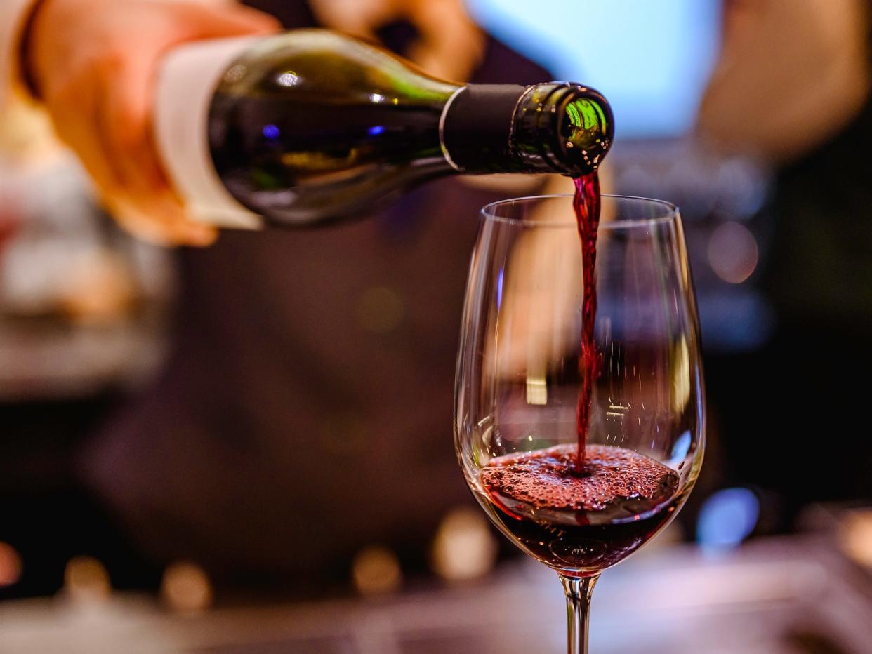 server pouting a glass of red wine into a glass