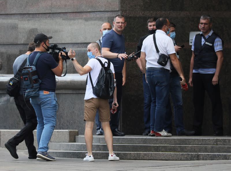 Journalists work outside a building before entering a bank where an unidentified man reportedly threatens to blow up a bomb, in Kyiv