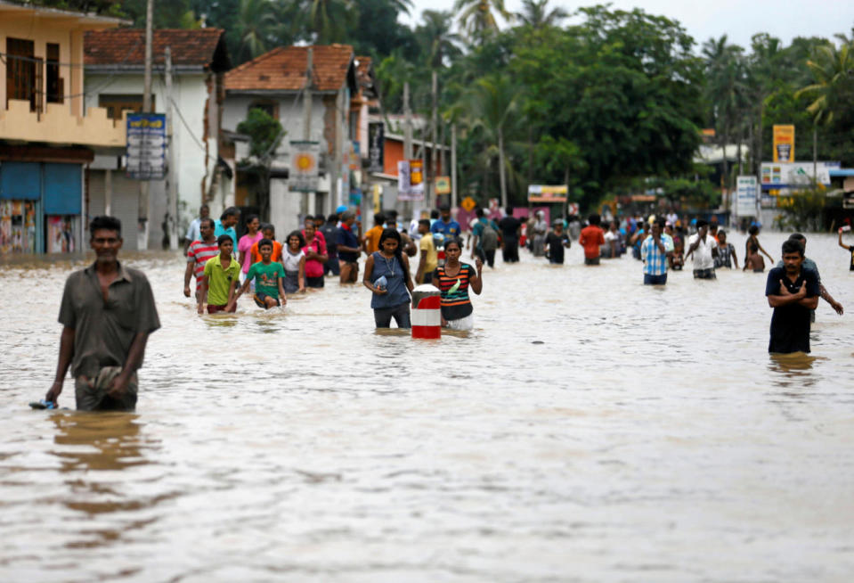 People walk on a flooded road after leaving their houses in Biyagama, Sri Lanka, May 17, 2016. (Reuters/Dinuka Liyanawatte)