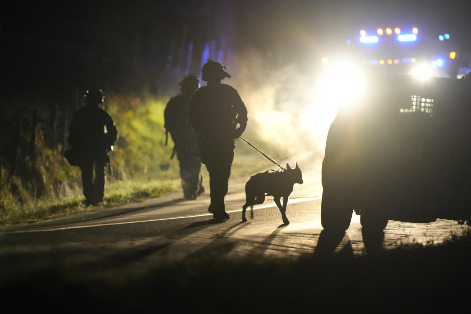 A member of law enforcement walks with a police dog outside a property on Meadow Road in Bowdoin, Maine, Thursday, Oct. 26, 2023. Hundreds of heavily armed police and FBI agents searched intensely for Robert Card, an Army reservist authorities say fatally shot a number of people at a bowling alley and a bar Wednesday. (AP Photo/Steven Senne)
