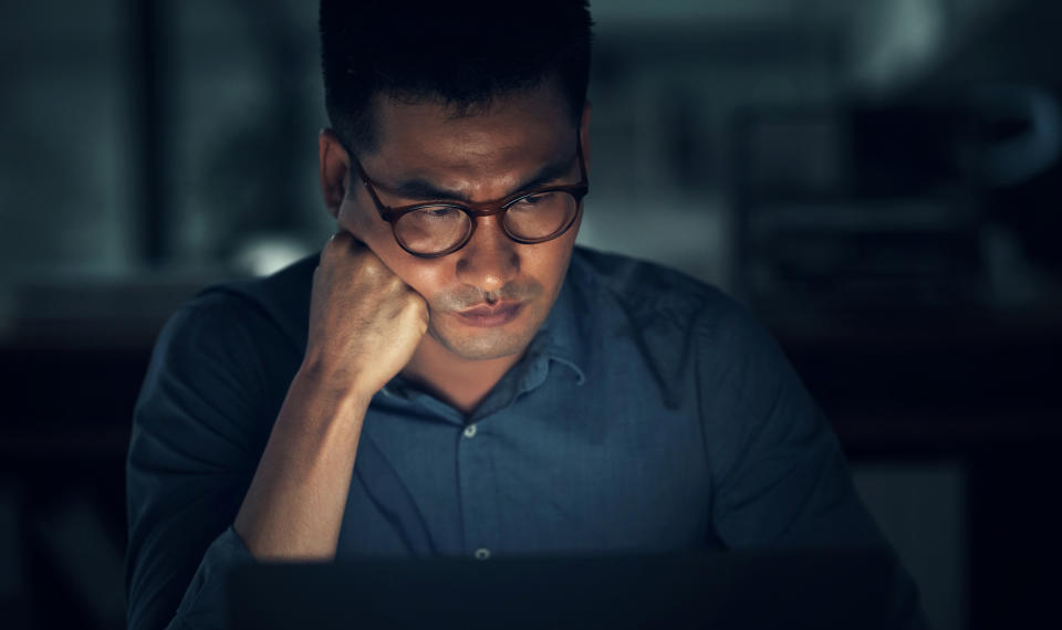 a man with a sad or stressed look while he's looking down at his computer