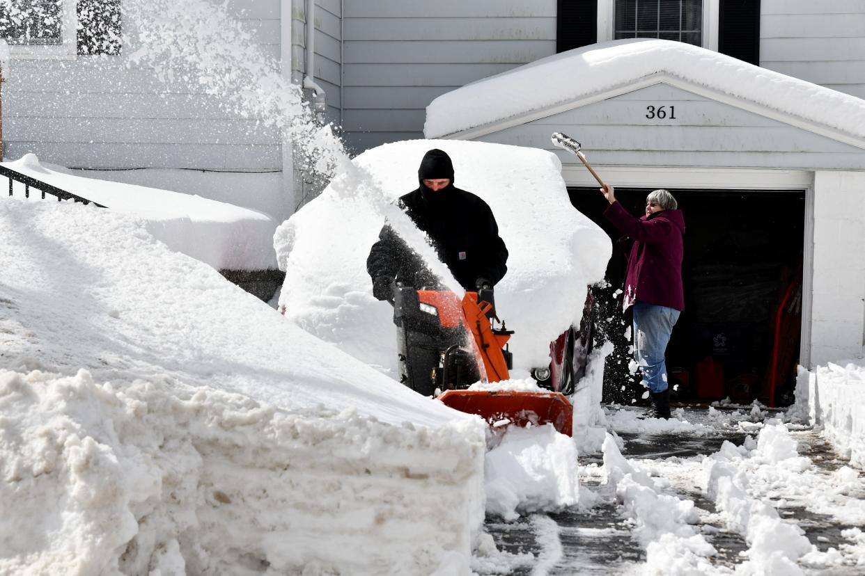 As Diane Drumm unburies her car, her son, Chris, clears her Pleasant Street driveway in Paxton with a snowblower Wednesday.