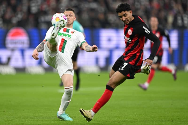 Augsburg's Jeffrey Gouweleeuw (L) and Frankfurt's Omar Marmoush battle for the ball during the German Bundesliga soccer match between Eintracht Frankfurt and FC Augsburg at Deutsche Bank Park. Arne Dedert/dpa