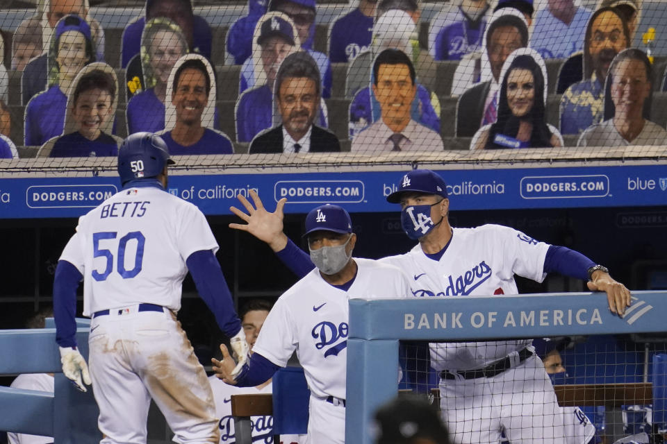 Los Angeles Dodgers' Mookie Betts (50) returns to the dugout after his solo home run, to congratulations from manager Dave Roberts, center, and bench coach Bob Geren during the ninth inning of the team's baseball game against the Arizona Diamondbacks on Wednesday, Sept. 2, 2020, in Los Angeles. (AP Photo/Marcio Jose Sanchez)