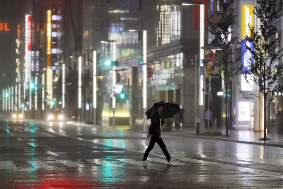 A man walks a pedestrian crossing at Ginza shopping district in the pouring rain due to Typhoon Hagibis in Tokyo Saturday, Oct. 12, 2019. A heavy downpour and strong winds pounded Tokyo and surrounding areas on Saturday as a powerful typhoon forecast as the worst in six decades approached landfall, with streets and train stations deserted and shops shuttered. (AP Photo/Eugene Hoshiko)